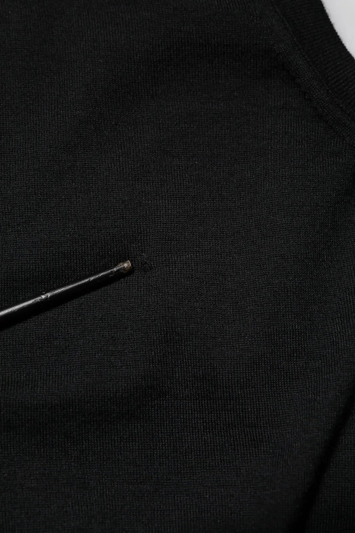 Tissu noir en maille avec une petite aiguille métallique reposant sur un débardeur sans manches en cachemire noir dolce & gabbana