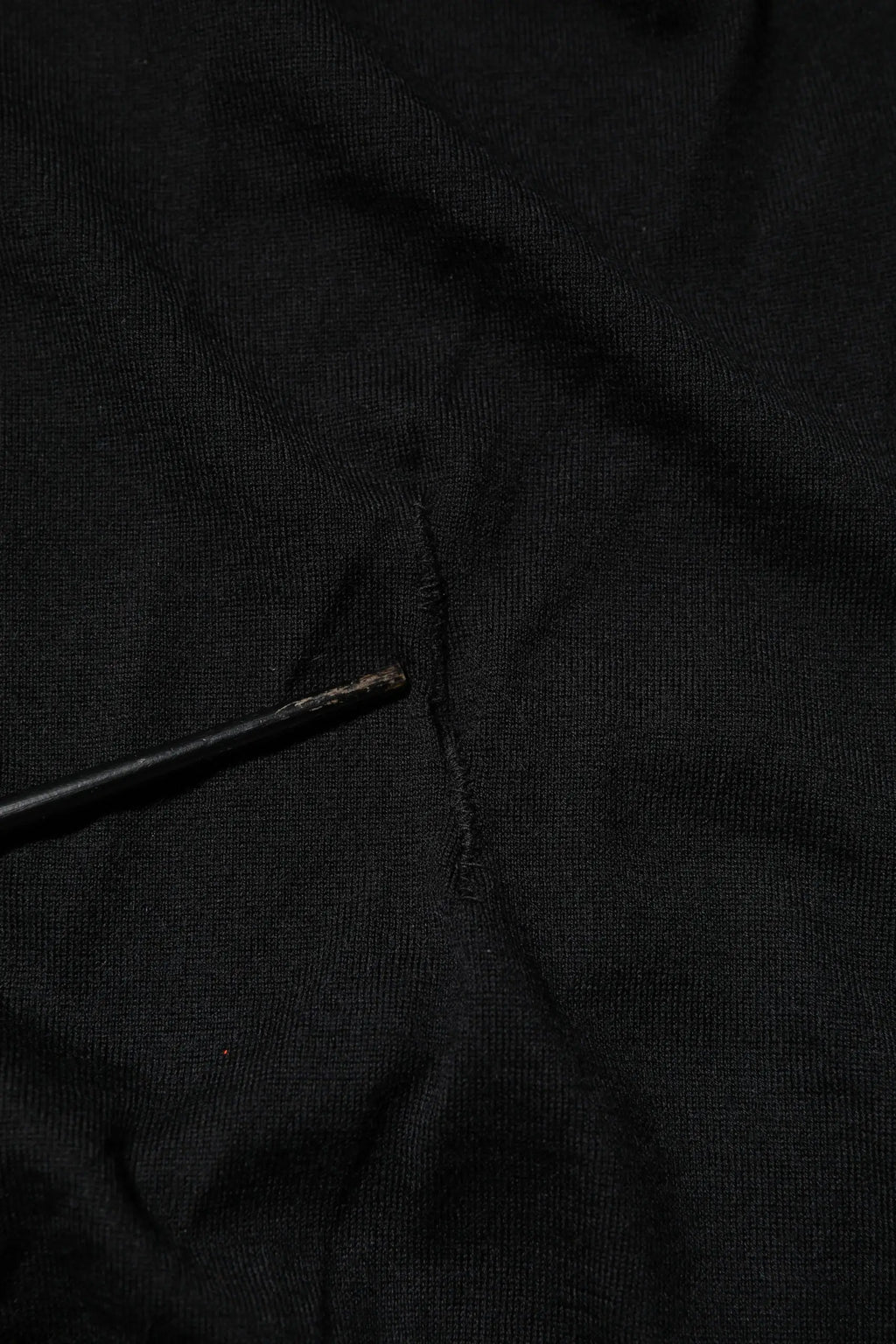 Dolce & Gabbana t-shirt noir en cachemire avec col en v et manches longues avec une petite déchirure au centre proddée doucement