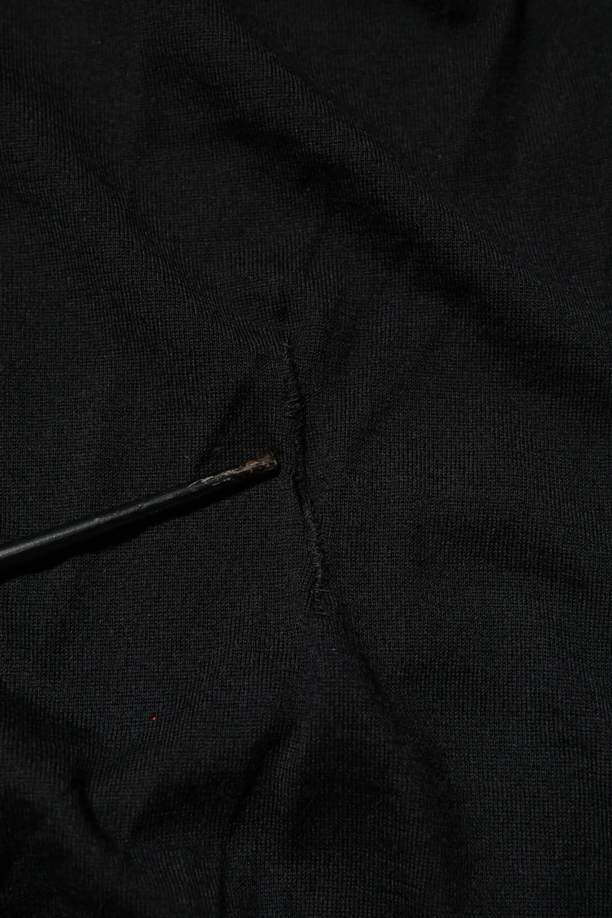 Dolce & Gabbana t-shirt noir en cachemire avec col en v et manches longues avec une petite déchirure au centre proddée doucement