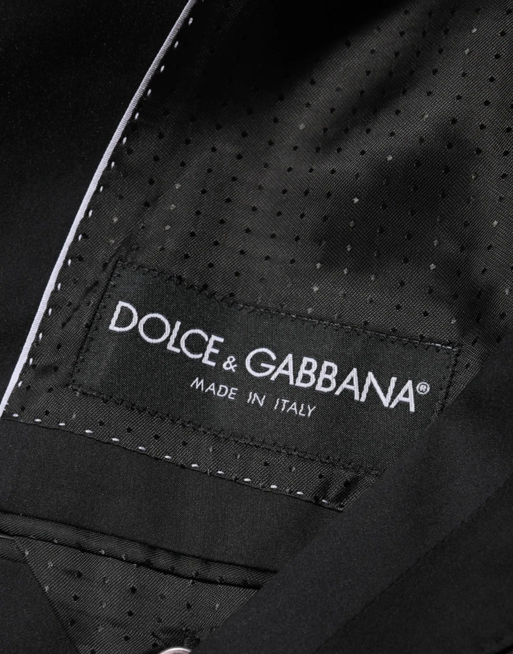 Étiquette en tissu perforé noire avec broderie blanche dolce & gabbana made in italy cousue à l’intérieur d’une veste blazer noire en coton à deux boutons