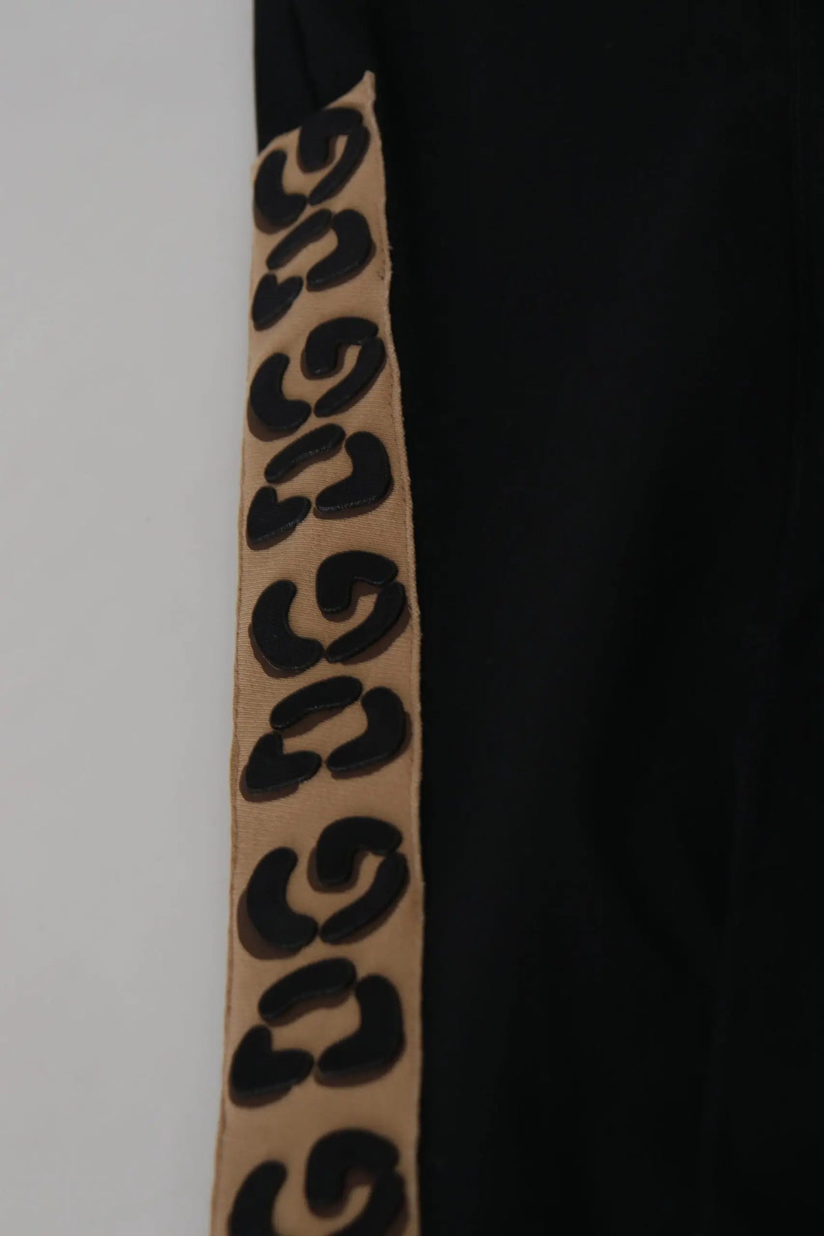 Bande en tissu léopard beige avec larges taches noires sur pantalon cropped en coton noir dolce gabbana avec taille élastique dg