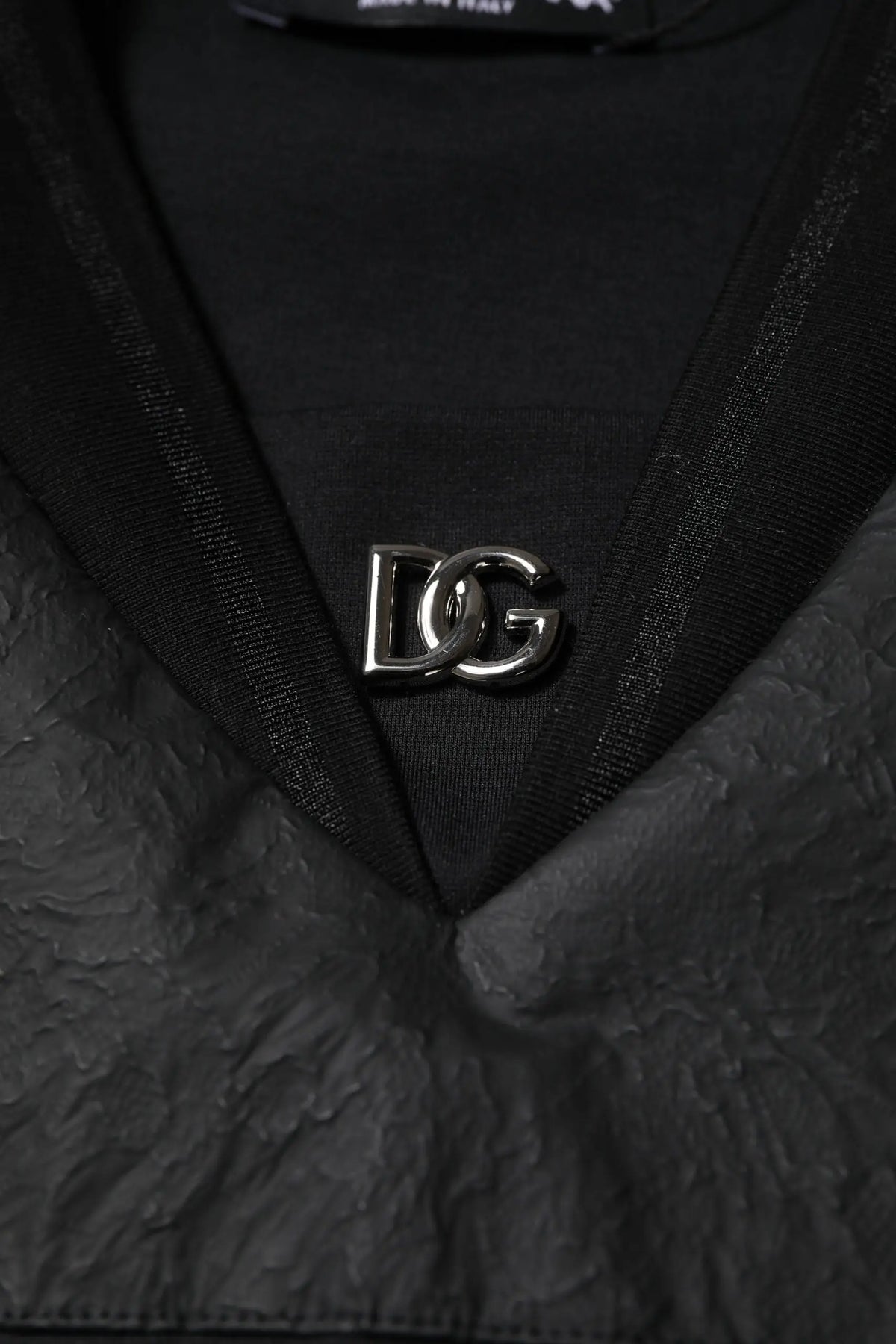 Une épingle logo dg métallique argentée sur un t-shirt dolce & gabbana noir en coton à manches courtes col v