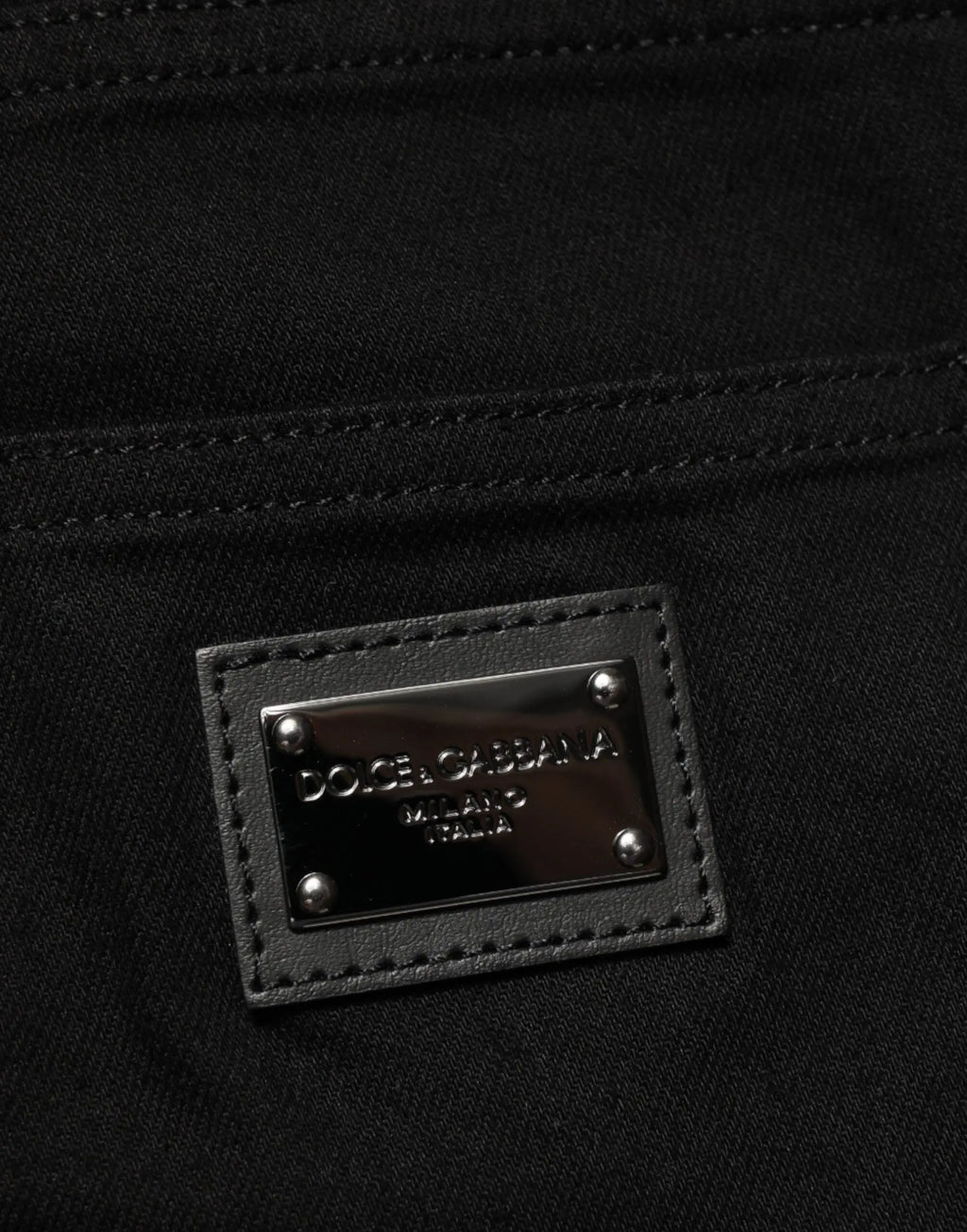 Patch en cuir noir avec plaque métallique argentée dolce & gabbana milano italia sur jean slim stretch coton noir homme