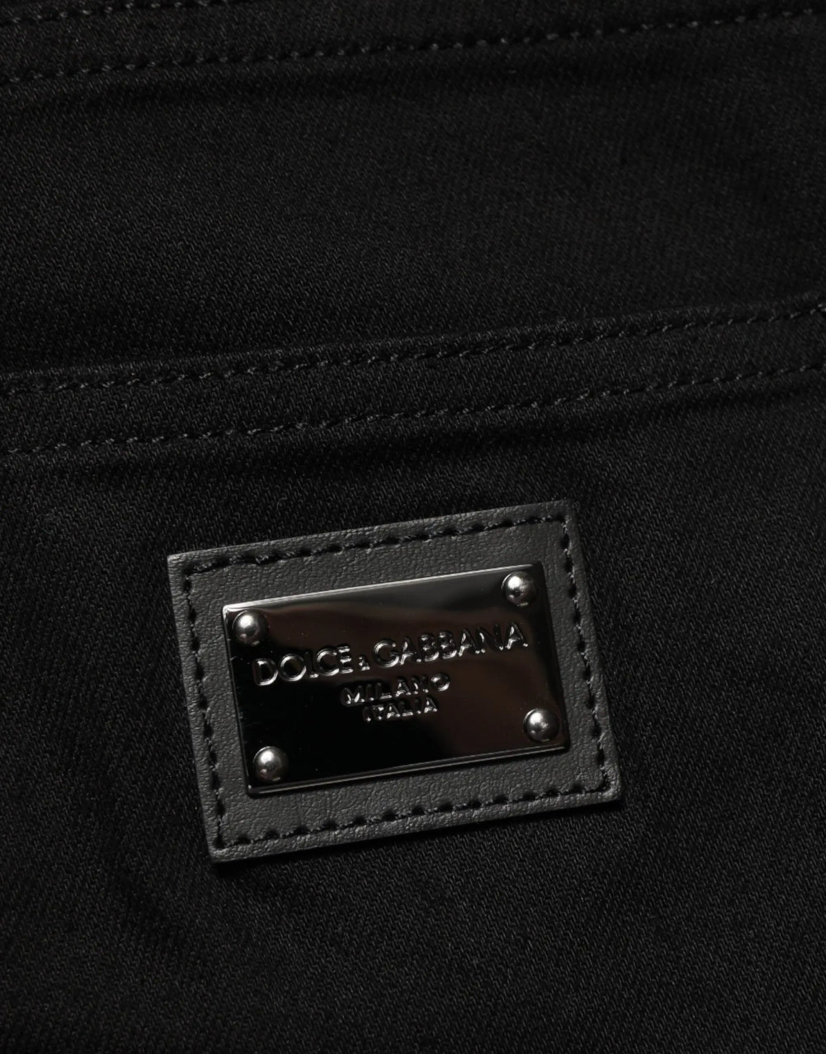 Patch en cuir noir avec plaque métallique argentée dolce & gabbana milano italia sur jean slim stretch coton noir homme