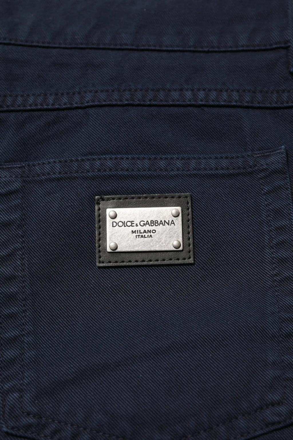 Jean denim noir tapered en coton dolce gabbana avec plaque métal argentée gravée dolce gabbana milano italia au dos