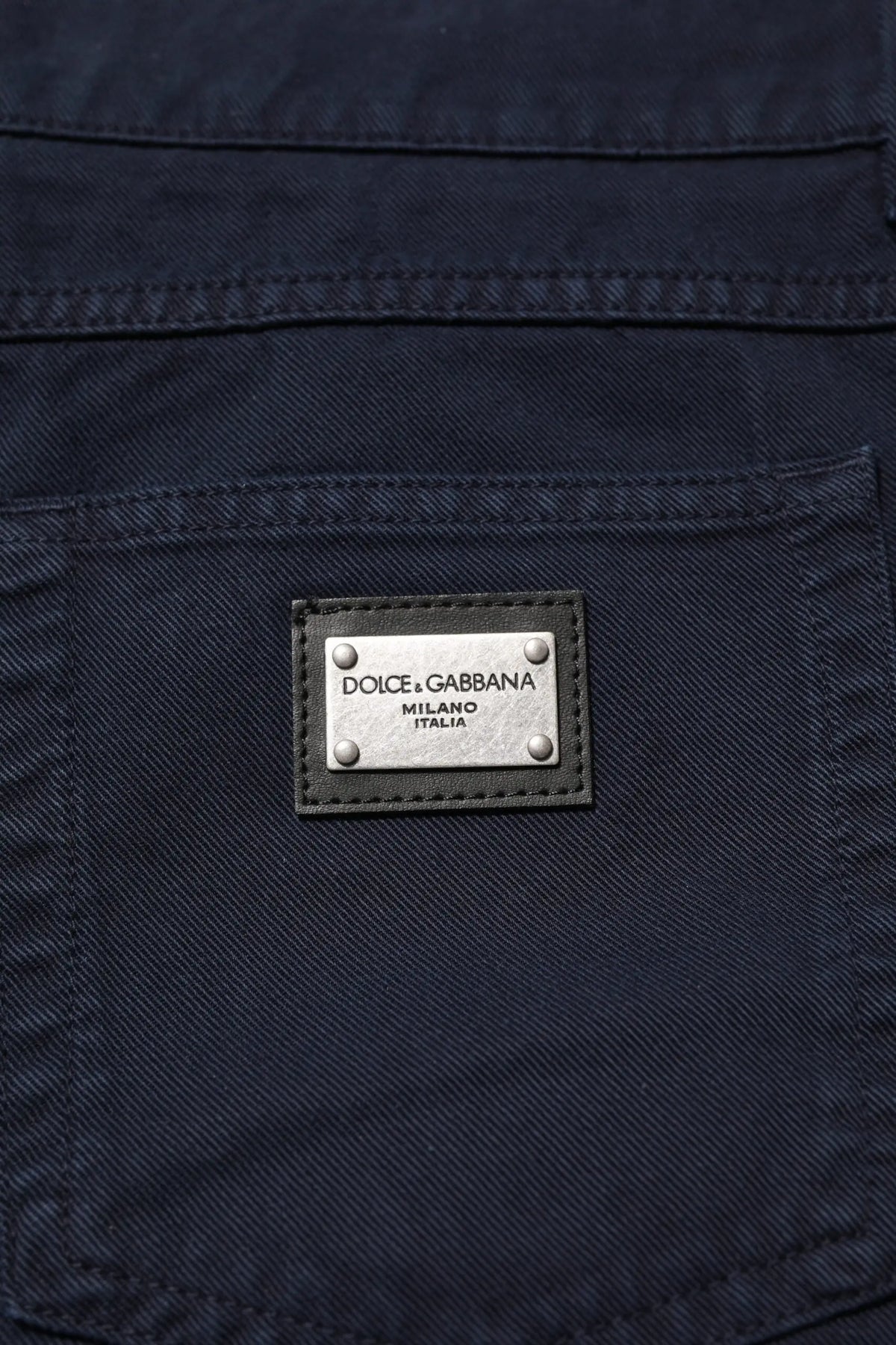 Jean denim noir tapered en coton dolce gabbana avec plaque métal argentée gravée dolce gabbana milano italia au dos