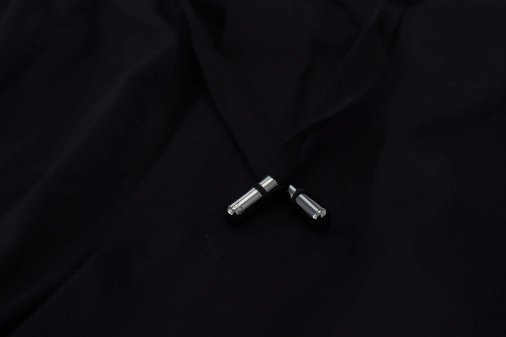 Deux tirettes en métal argenté avec bandes en caoutchouc noir sur pantalon jogger homme dolce & gabbana noir imprimé dg