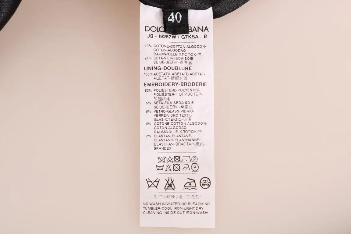 Étiquette de soin en tissu blanc avec texte noir sur le dos du pull dolce & gabbana noir en brocart fairy tale avec zip