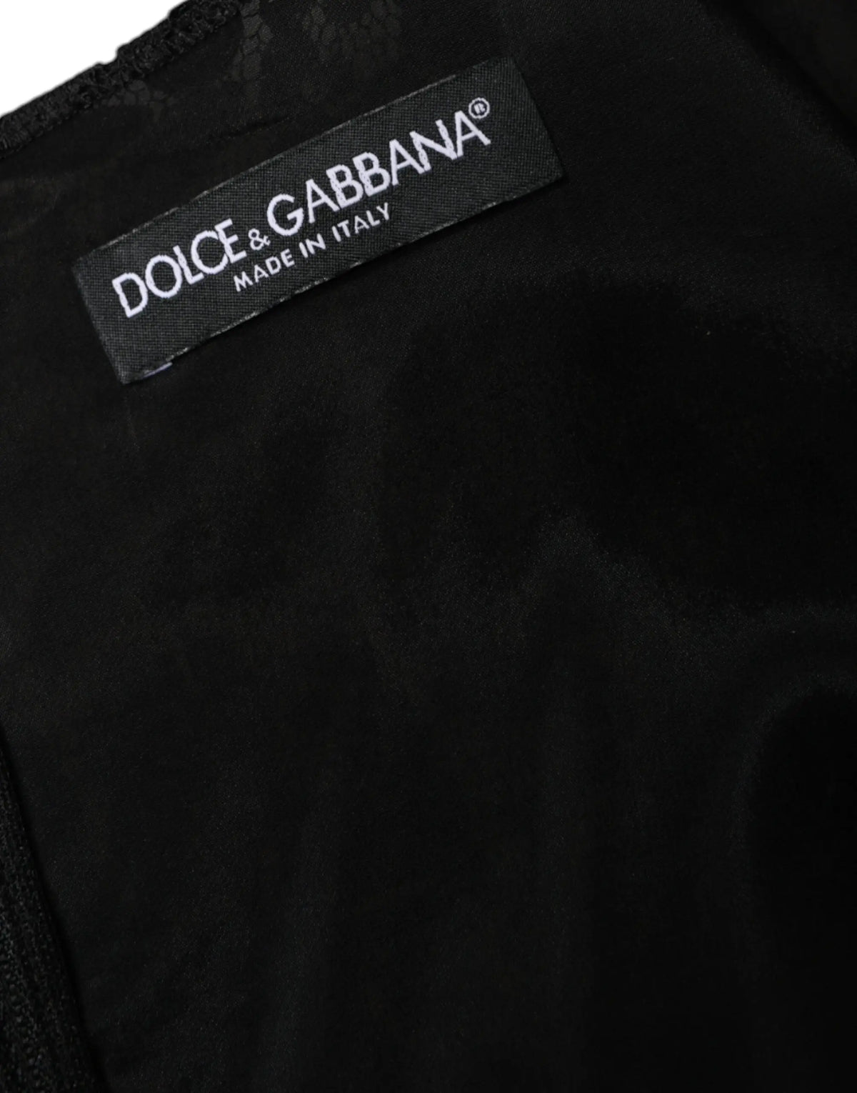 Étiquette noire dolce gabbana avec texte brodé blanc sur une robe mini noire en dentelle florale sans manches