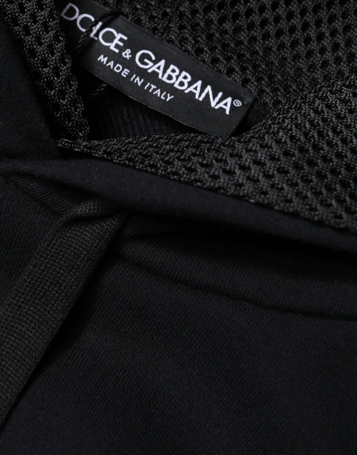 Étiquette dolce gabbana noire avec texte blanc made in italy cousue dans le col d un sweat à capuche noir en maille homme