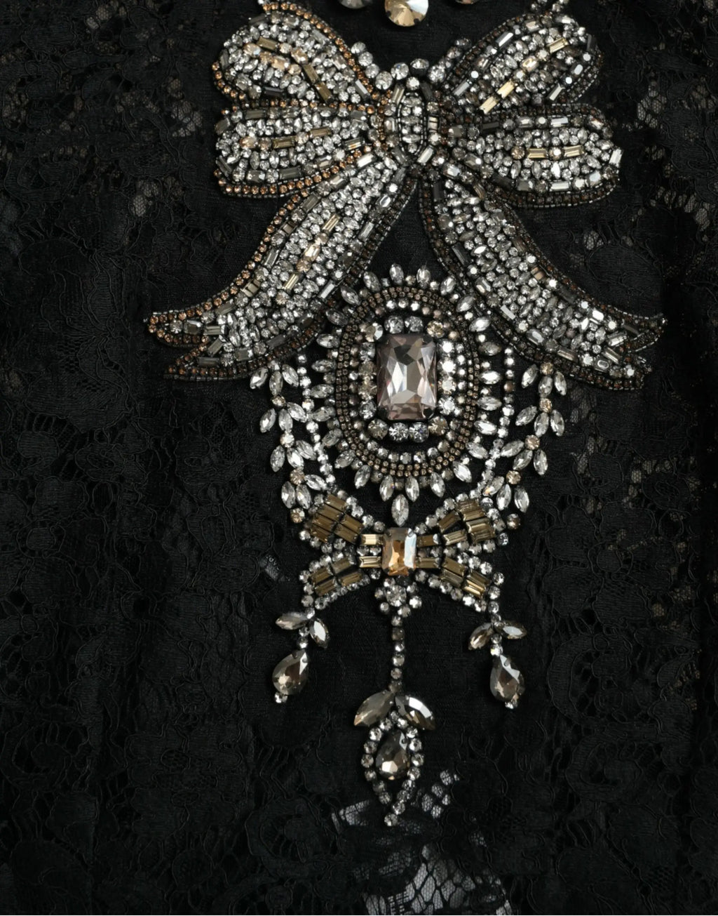 Broche en forme de nœud en argent et or avec strass sur robe Dolce & Gabbana en dentelle noire et cristaux
