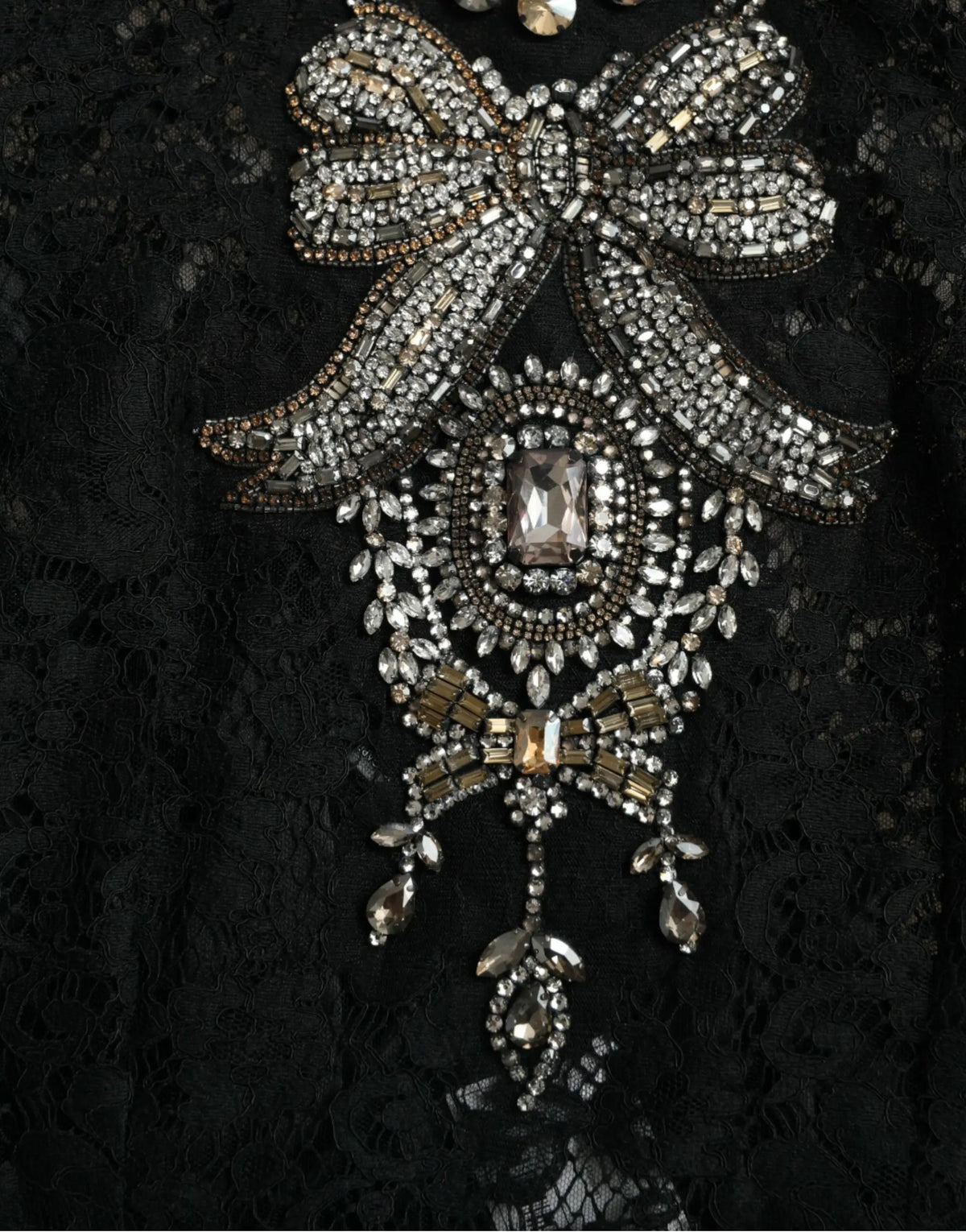 Broche en forme de nœud en argent et or avec strass sur robe Dolce & Gabbana en dentelle noire et cristaux