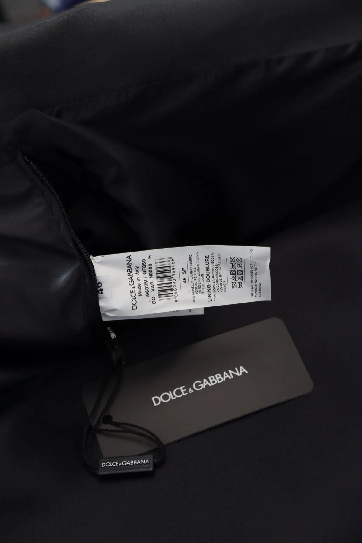 Étiquette noire dolce gabbana avec texte blanc et code-barres sur veste zippée en cuir noir biker