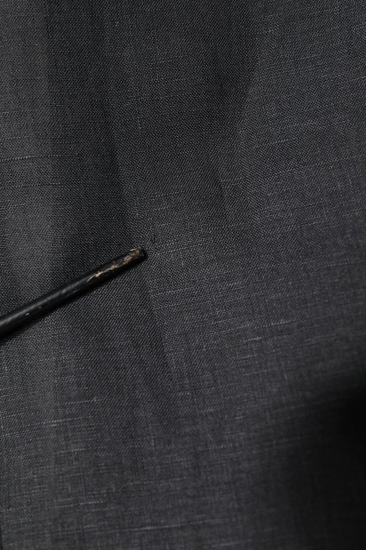 Crayon noir avec pointe usée posé sur tissu gris foncé texturé près d’un manteau blazer homme dolce gabbana noir en lin simple boutonnage