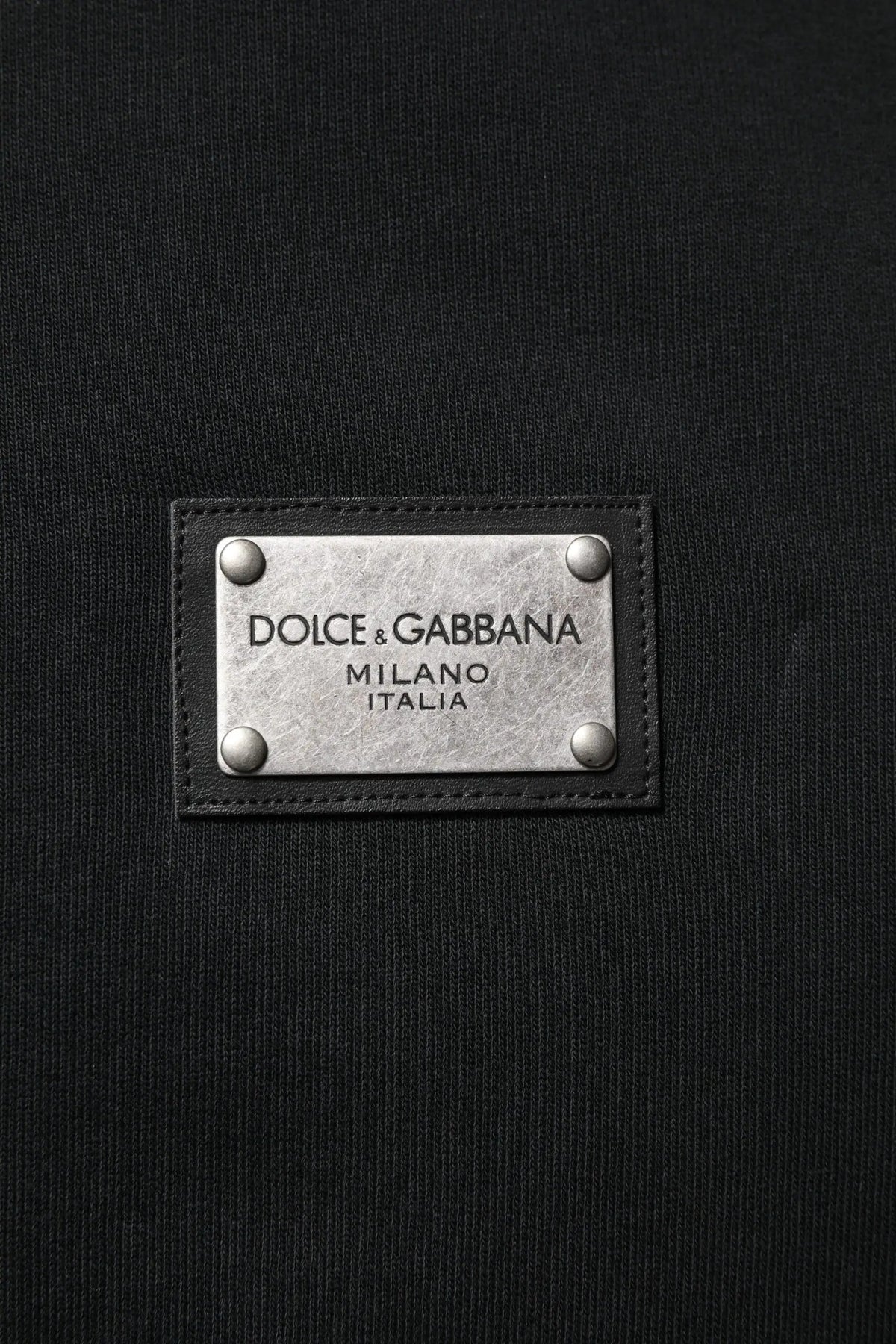 Étiquette dolce & gabbana milano italia noire avec plaque métal argenté et bordure cuir noir sur sweat à capuche homme noir