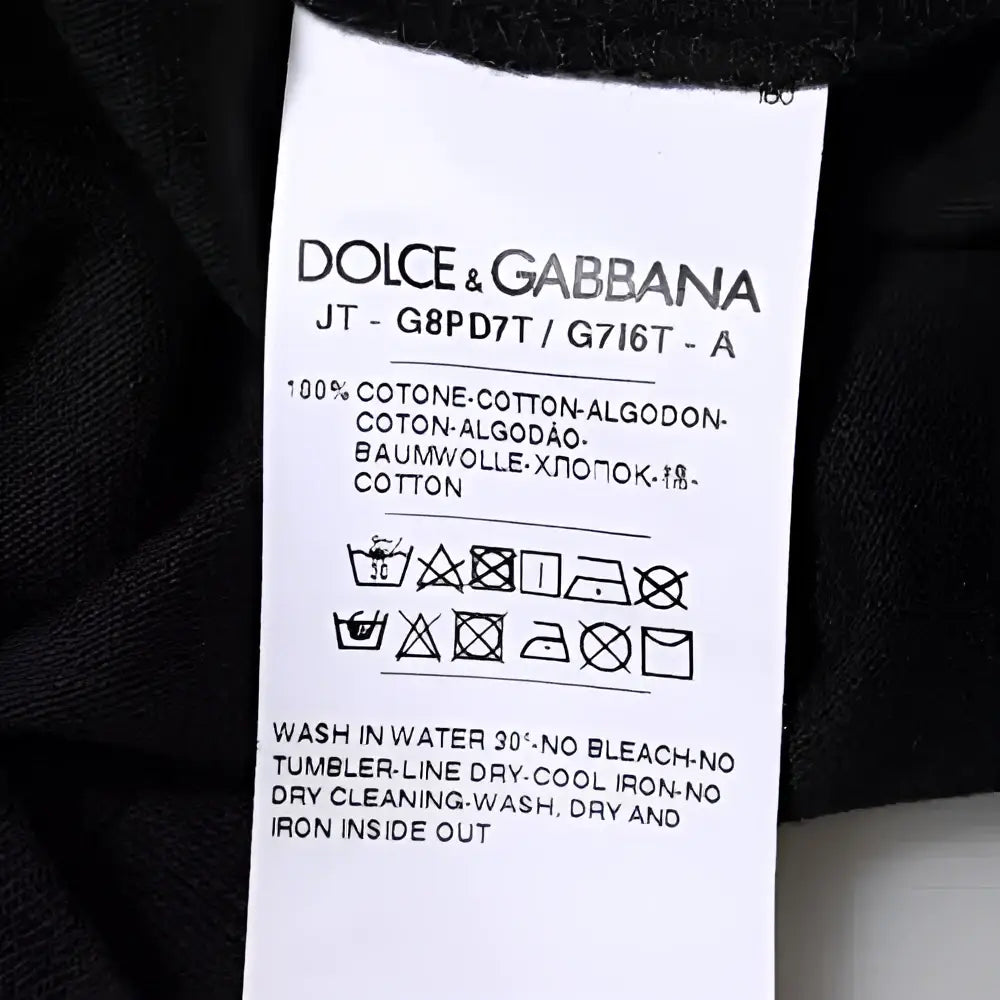 Étiquette d’entretien blanche dolce gabbana avec texte noir sur la composition et les instructions de lavage du t-shirt noir en coton