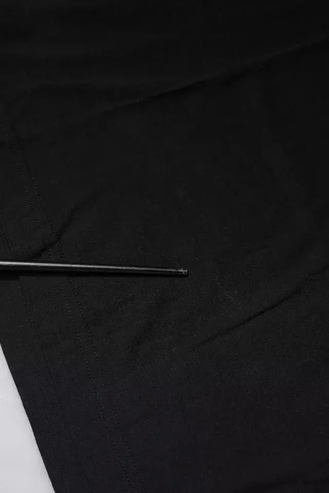 Une aiguille métallique élégante posée en diagonale sur un tissu noir lisse avec un t shirt dolce gabbana noir coton manches courtes logo
