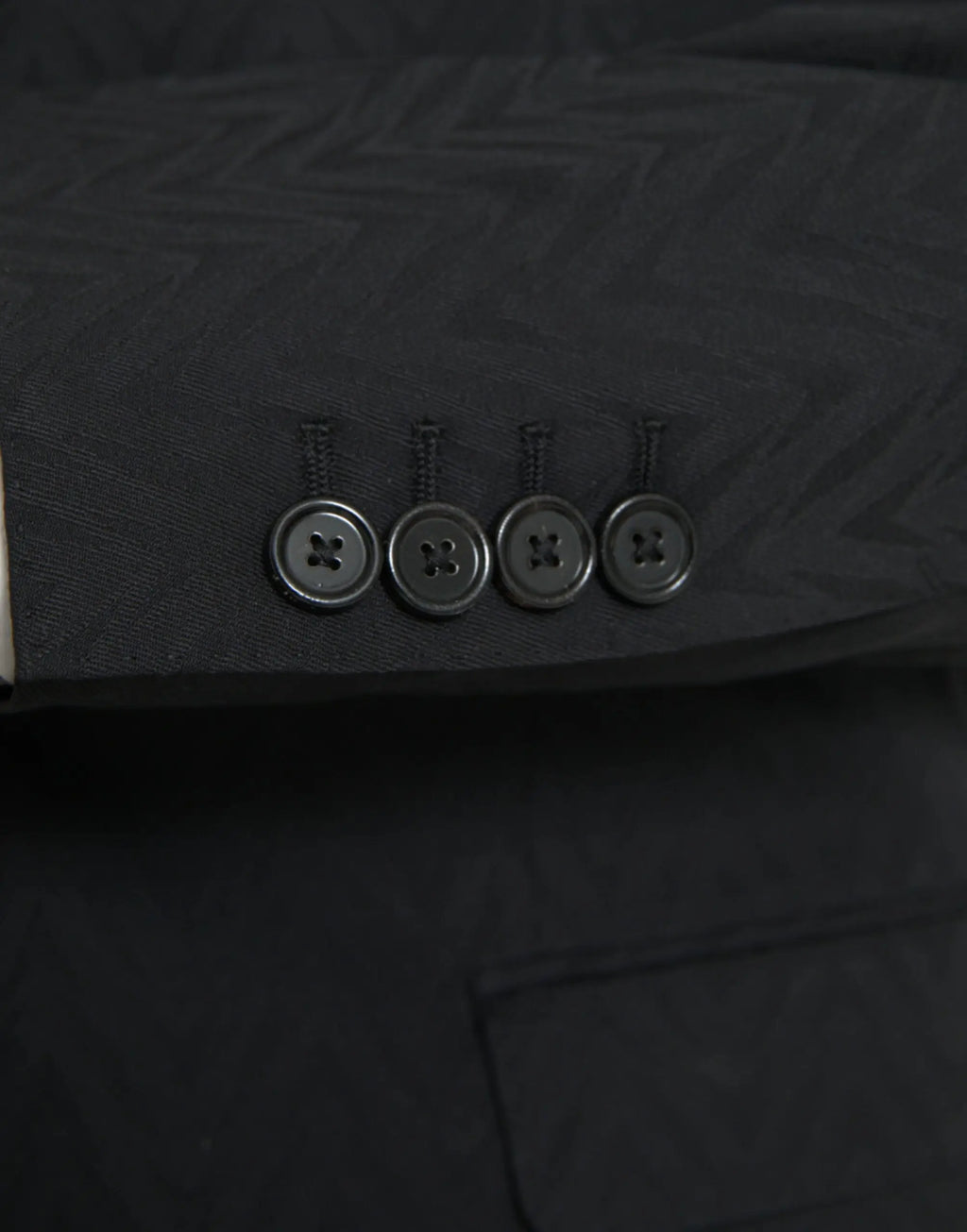 Quatre boutons métalliques gris foncé avec un motif croisé sur le revers d’une veste noire martini slim fit dolce & gabbana