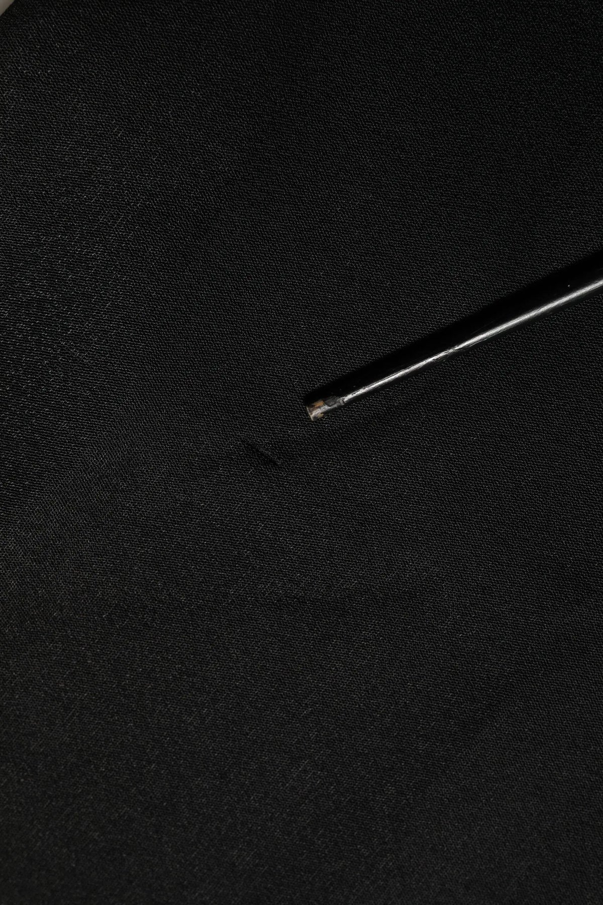 Une aiguille métallique élégante au bout argenté repose sur un tissu noir du sweat-shirt dolce & gabbana noir logo dg cristal