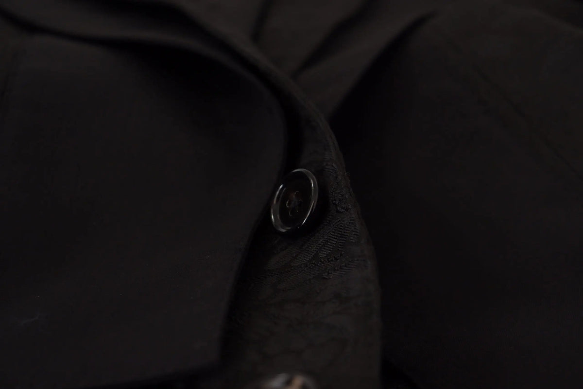Un bouton noir élégant à finition métallique subtile sur un tissu foncé du costume formel martini 2 pièces en polyester de dolce & gabbana