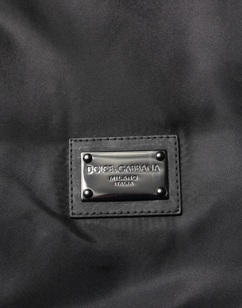 Patch en cuir noir dolce & gabbana milano italia avec plaque métallique et rivets sur veste bomber logo polyester