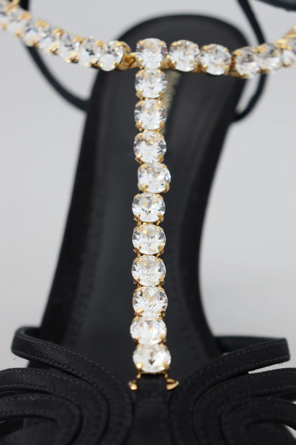 Une chaîne en or étincelante ornée de cristaux clairs drape élégamment la bride en satin noir des sandales dolce & gabbana