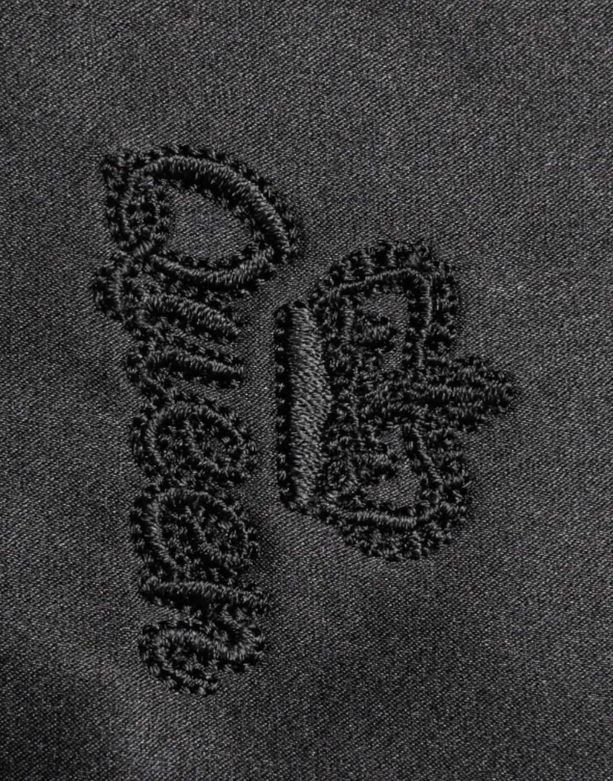 Logo brodé noir sur tissu denim foncé du chemisier dolce & gabbana en soie noire avec col ascot et boutons
