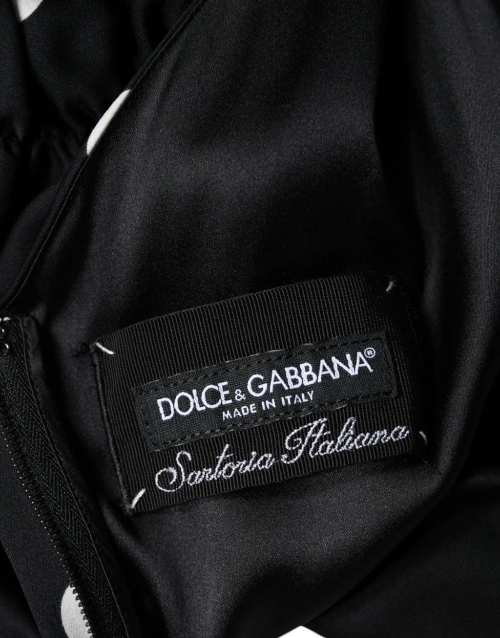 Étiquette noire dolce & gabbana en soie brodée en blanc sur l’intérieur d’une robe midi à pois noirs en soie