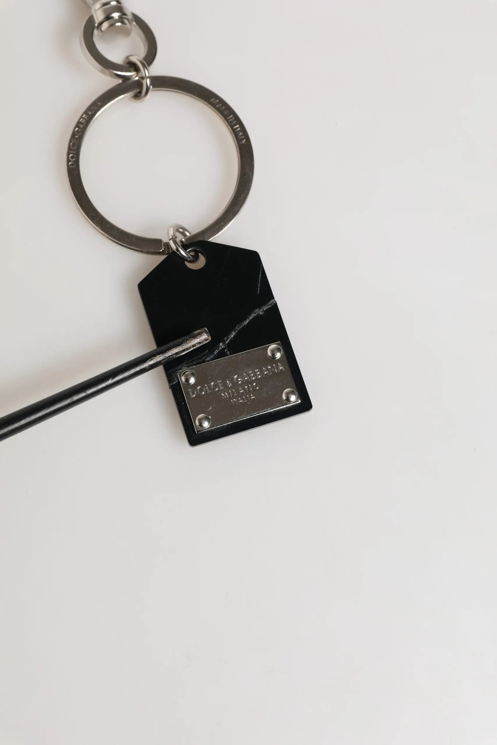 Porte-clés dolce & gabbana en marbre noir avec plaque en métal argenté gravée dolce & gabbana milano fixée par quatre vis