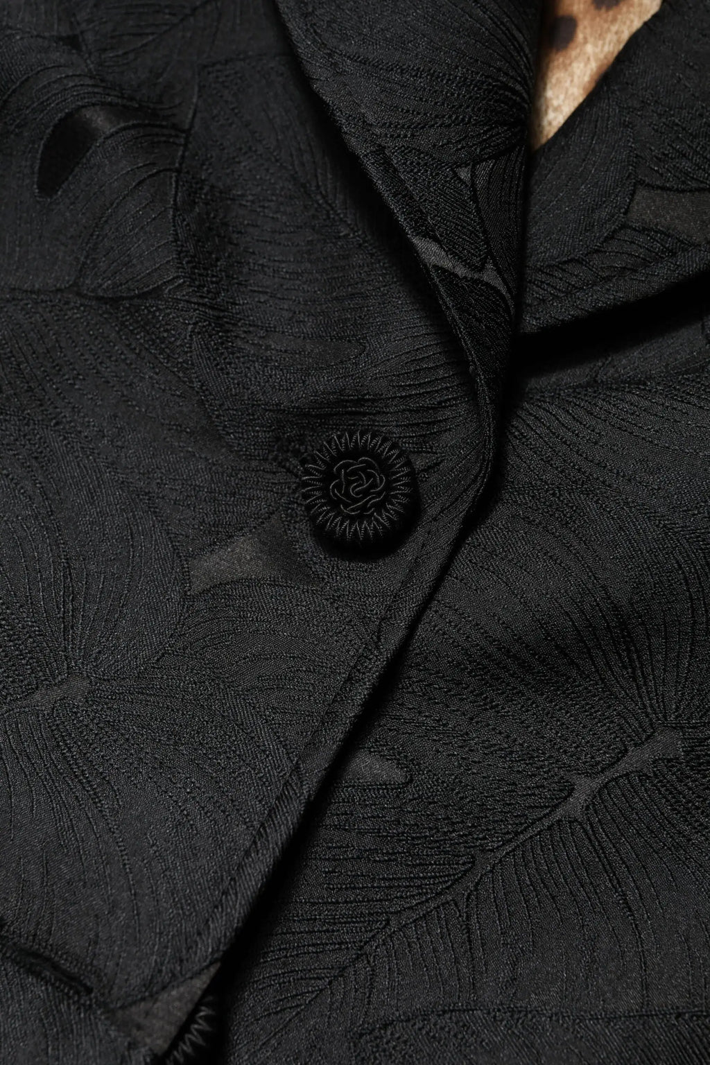 Bouton noir délicat avec motif rayons de soleil sur tissu texturé à motifs de feuilles du trench Dolce & Gabbana