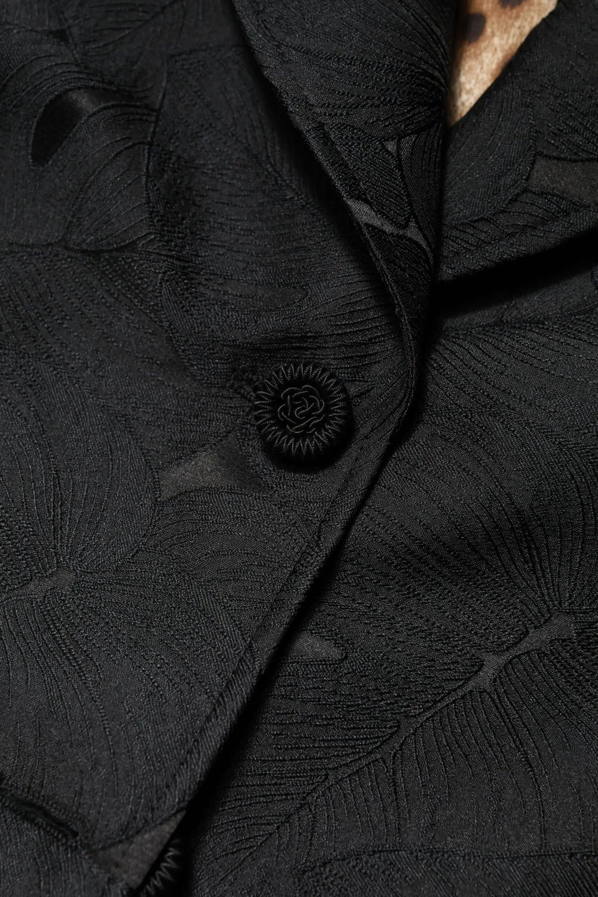 Bouton noir délicat avec motif rayons de soleil sur tissu texturé à motifs de feuilles du trench Dolce & Gabbana
