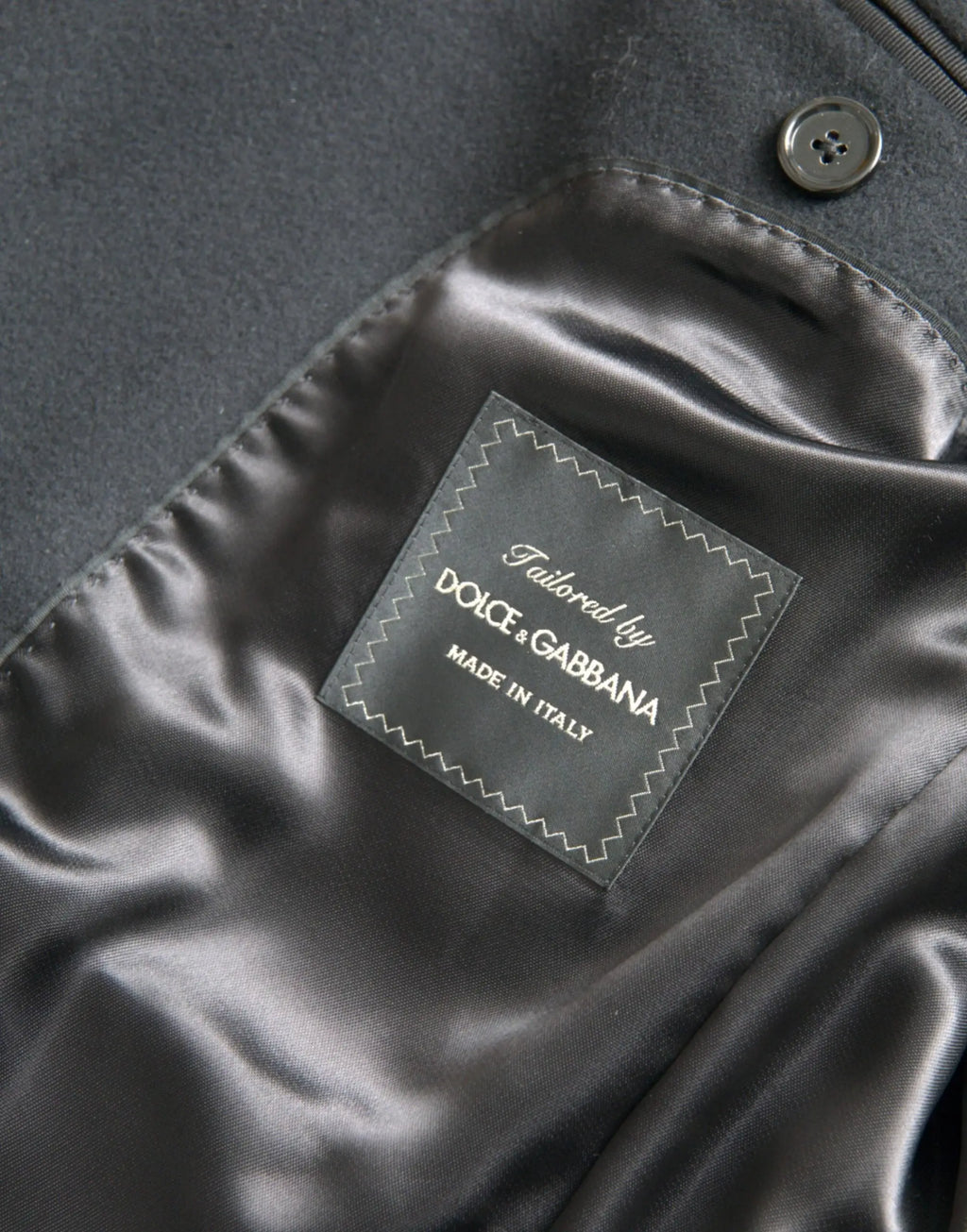 Étiquette en satin noir avec couture blanche en zigzag sur trench coat noir tailored by dolce & gabbana made in italy