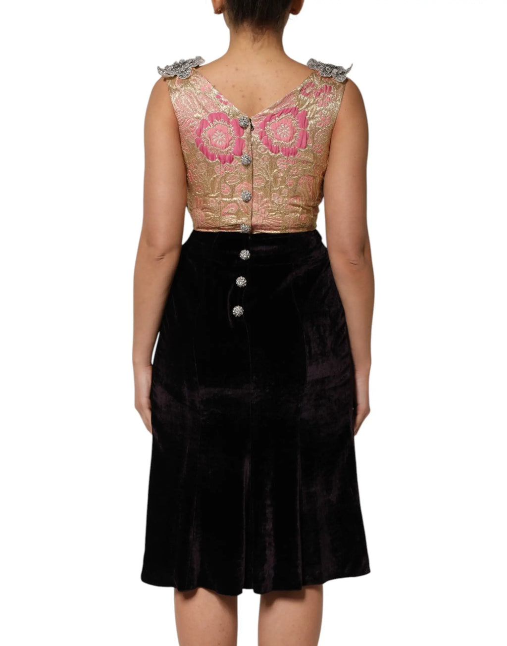 Une femme porte une robe dolce & gabbana noire en velours avec ornement floral et un haut orné brodé rose et or