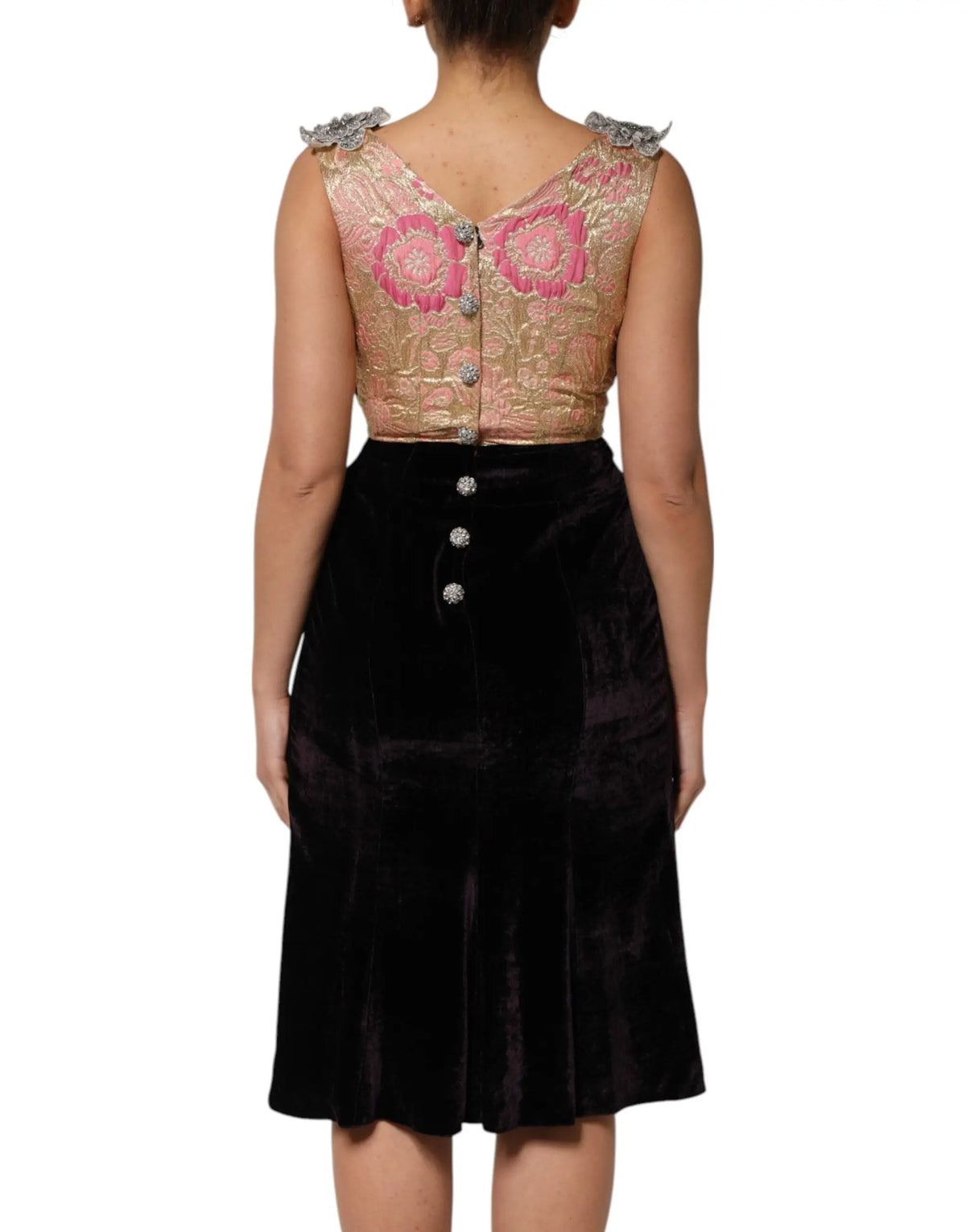 Une femme porte une robe dolce & gabbana noire en velours avec ornement floral et un haut orné brodé rose et or