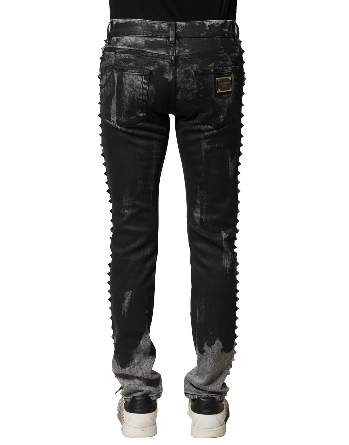 Jean skinny en denim noir délavé dolce & gabbana avec effet distressed, bordure cloutée et patch doré au dos