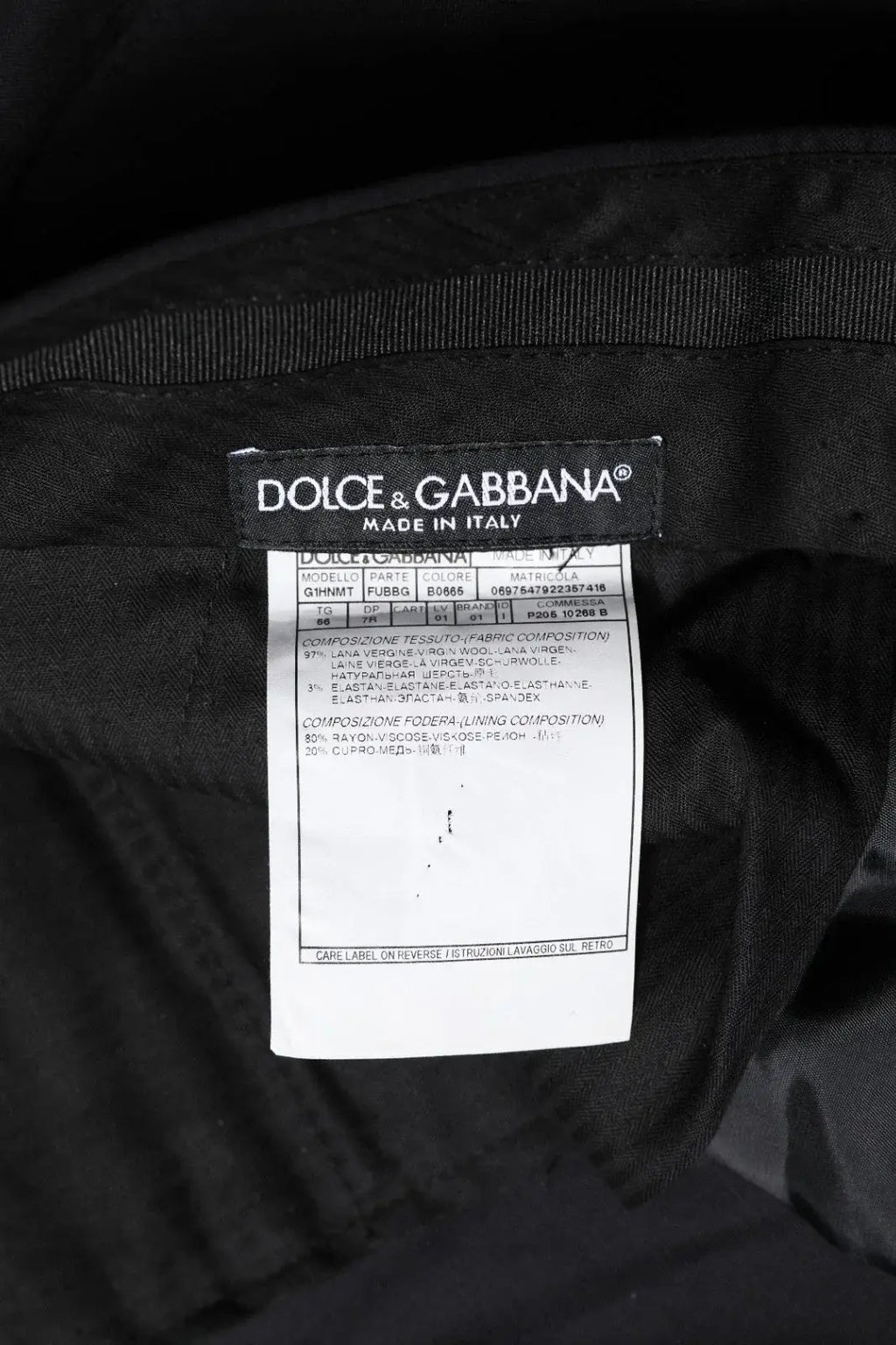 Étiquette noire dolce & gabbana avec texte blanc indiquant que le pantalon en laine noire pour homme est fabriqué en italie