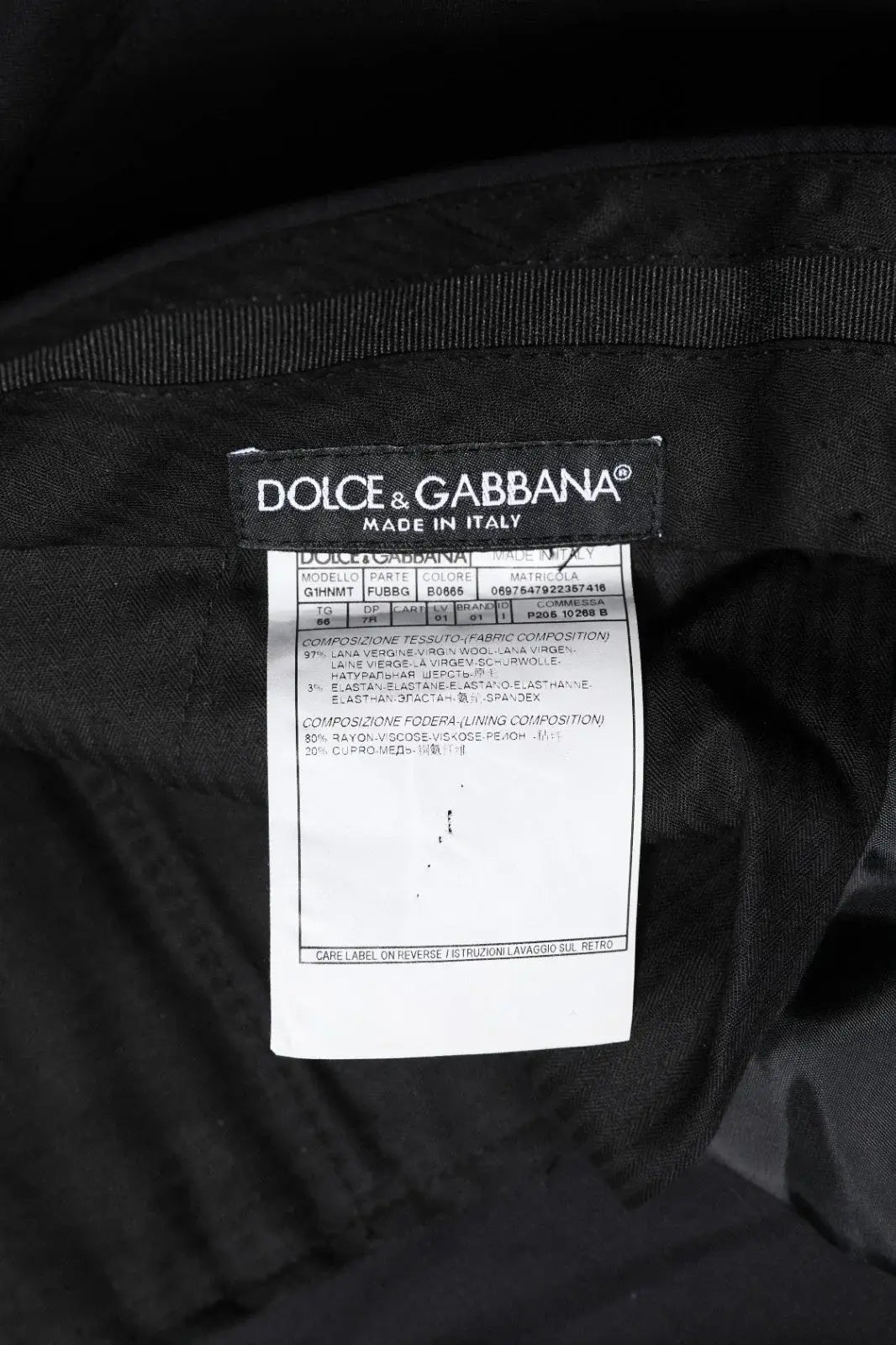 Étiquette noire dolce & gabbana avec texte blanc indiquant que le pantalon en laine noire pour homme est fabriqué en italie
