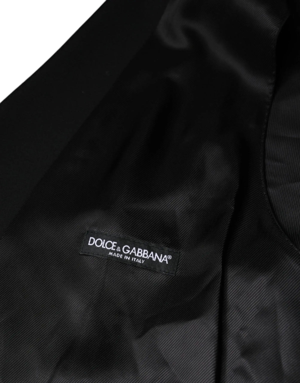 Étiquette noire dolce & gabbana en tissu foncé avec texte blanc pour gilet homme formel en laine noire