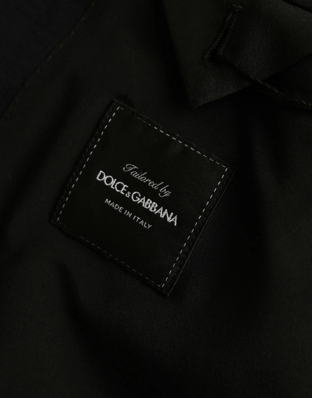 Patch en cuir noir avec bordure blanche brodée tailored by dolce & gabbana made in italy sur manteau laine noir