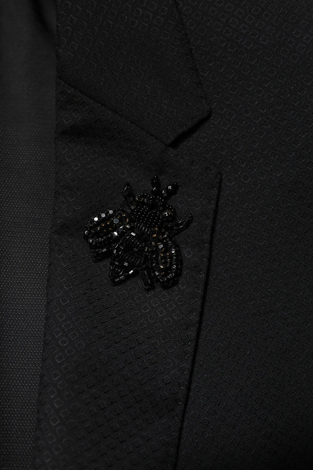 Une épingle abeille en perles noires orne le revers d un costume dolce gabbana noir en laine à deux pièces