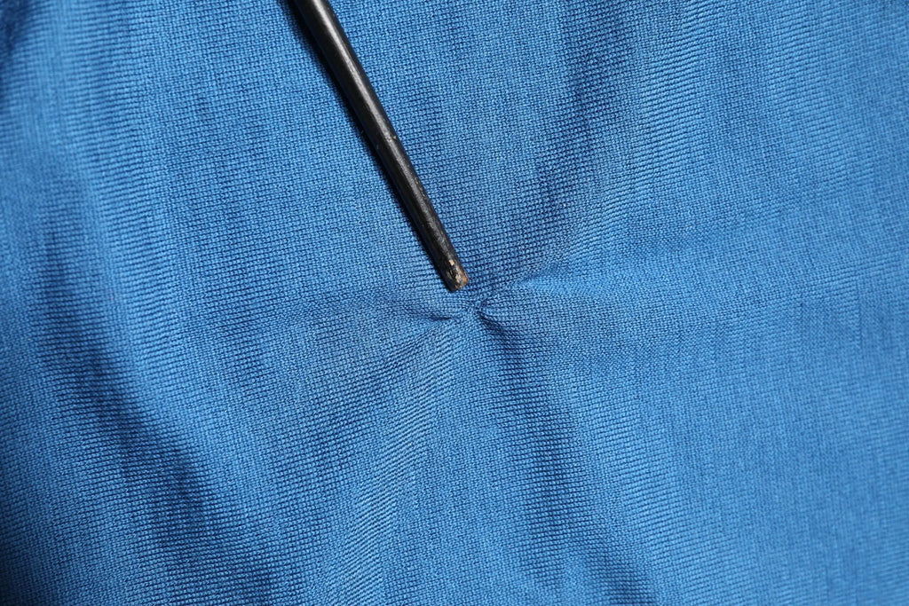 Aiguille noire traversant un tissu bleu vif en maille dans un pull col v couronne en cachemire bleu dolce gabbana