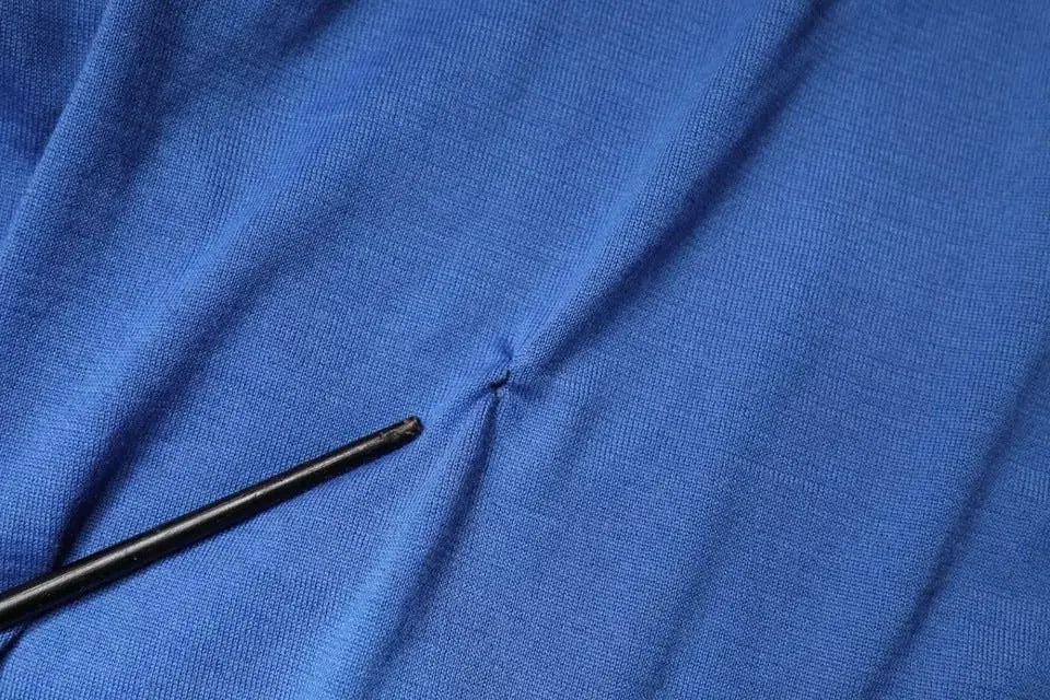 Un crochet noir repose sur un tissu bleu vif en maille pour un polo homme dolce gabbana en cachemire manches courtes
