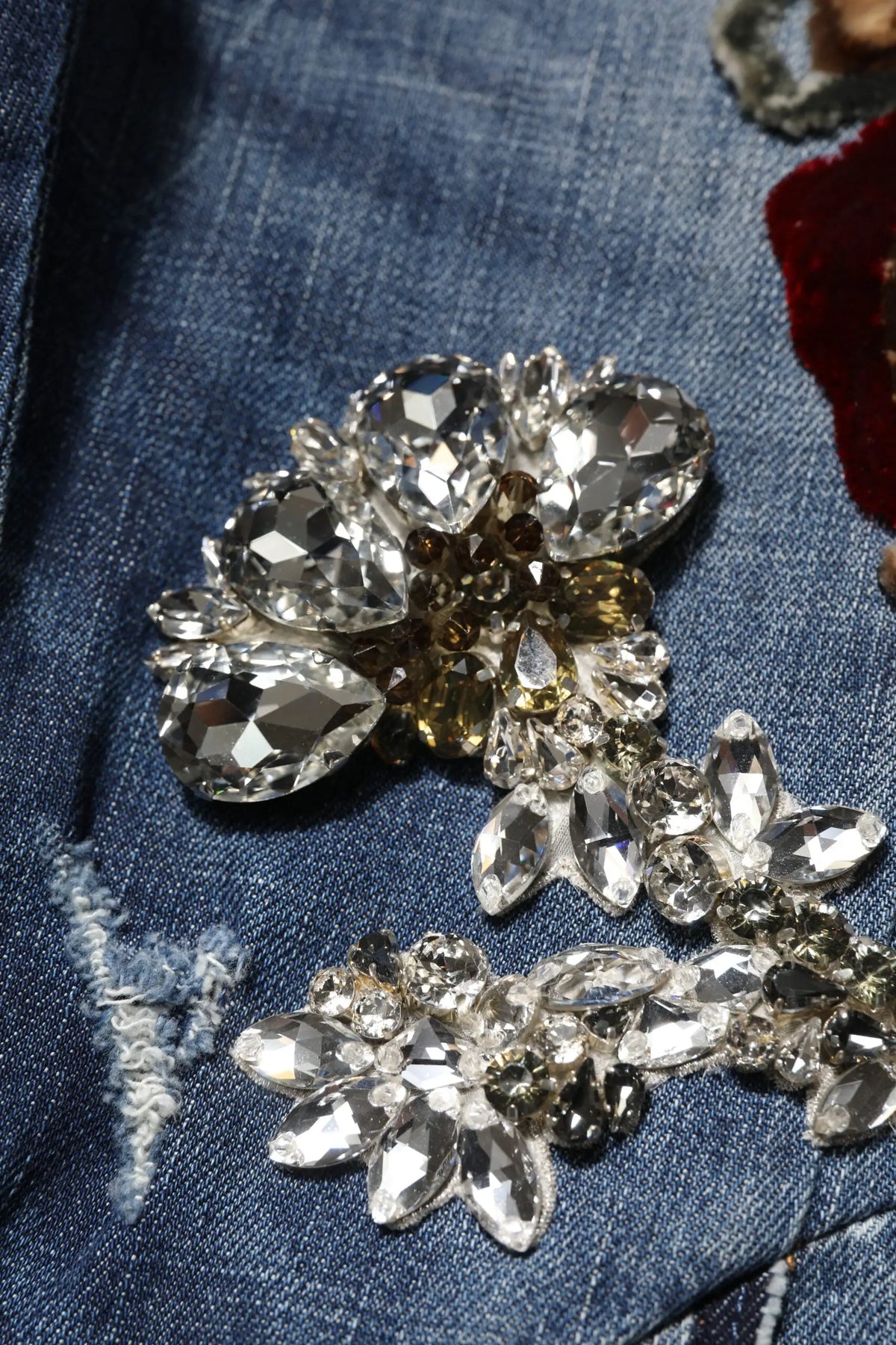 Broche florale étincelante à strass clairs et ambrés sur cadre métallique délicat sur jean en denim bleu dolce & gabbana