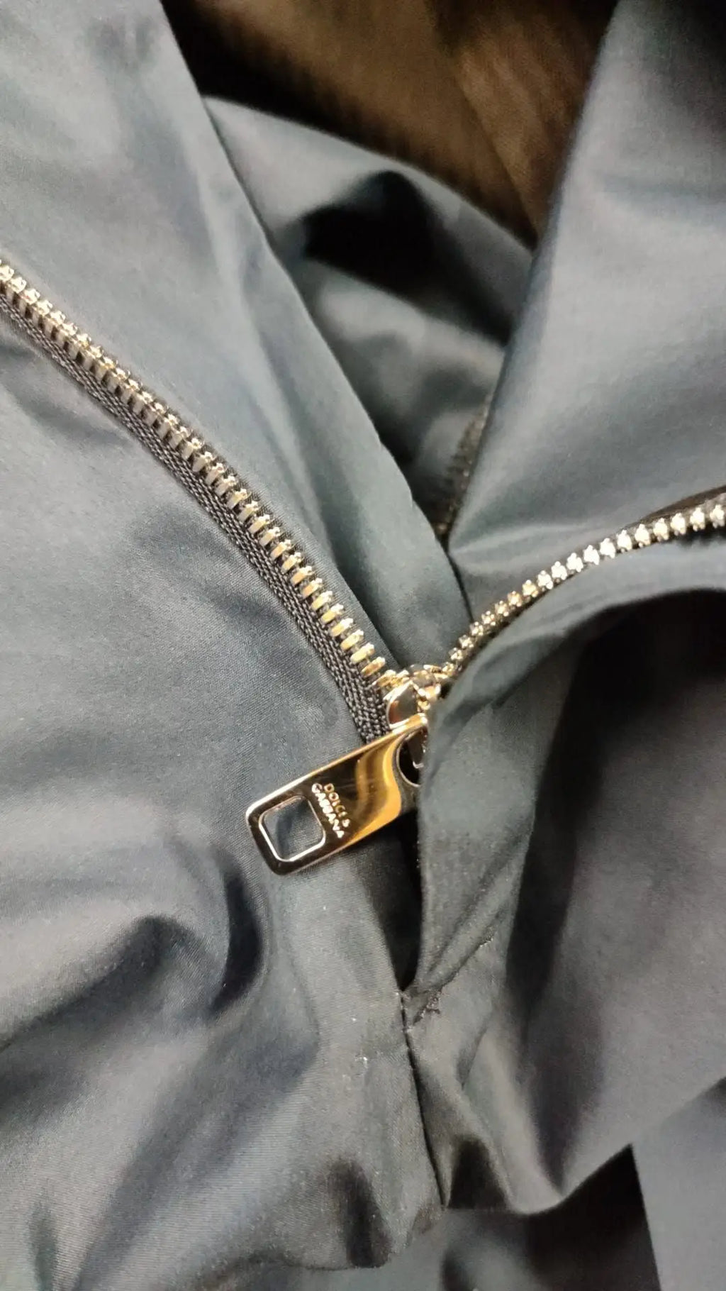 Une fermeture éclair métallique or sur tissu gris mat d une veste accompagnant un pantalon chino bleu en coton et soie dolce & gabbana