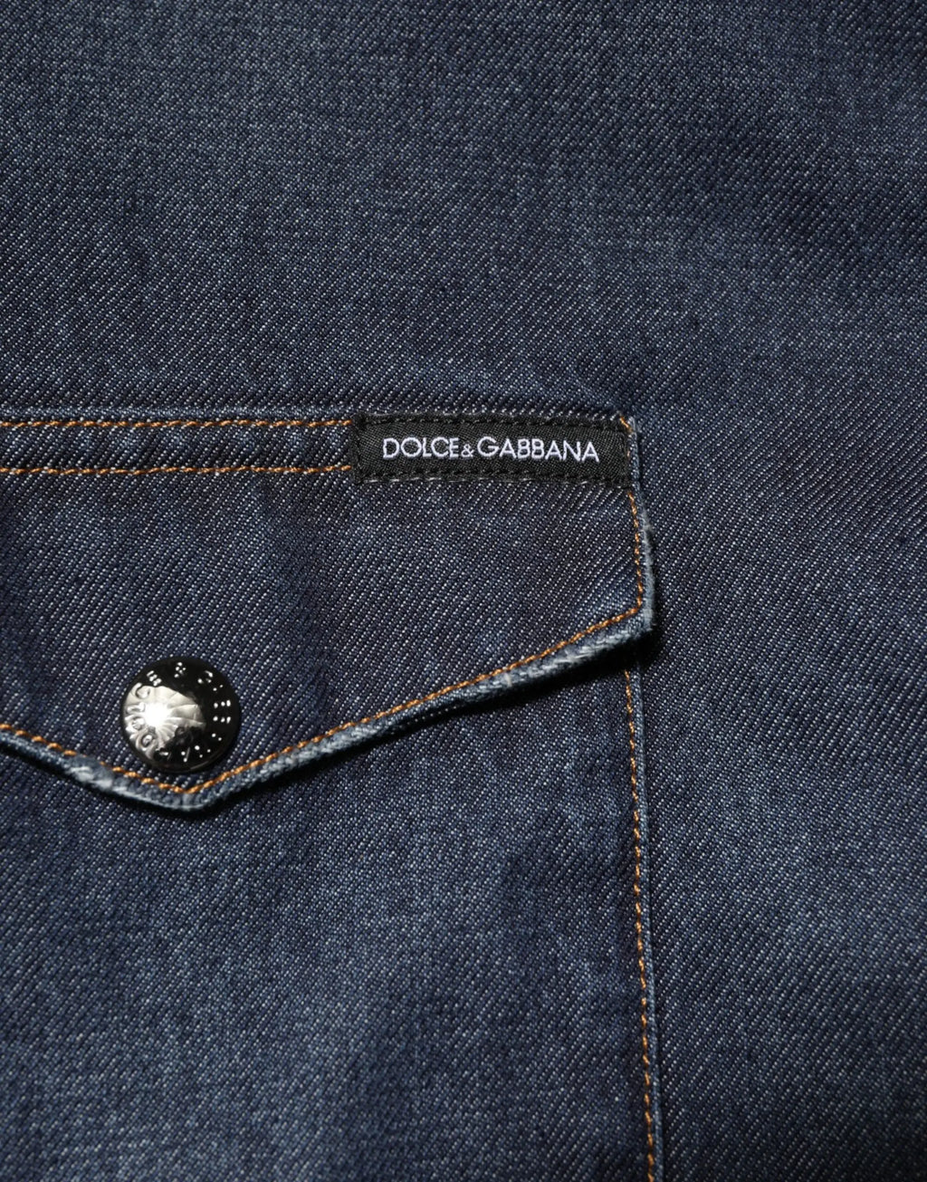 Poche de veste en jean bleu foncé avec étiquette noire dolce & gabbana et bouton argenté sur chemise homme casual