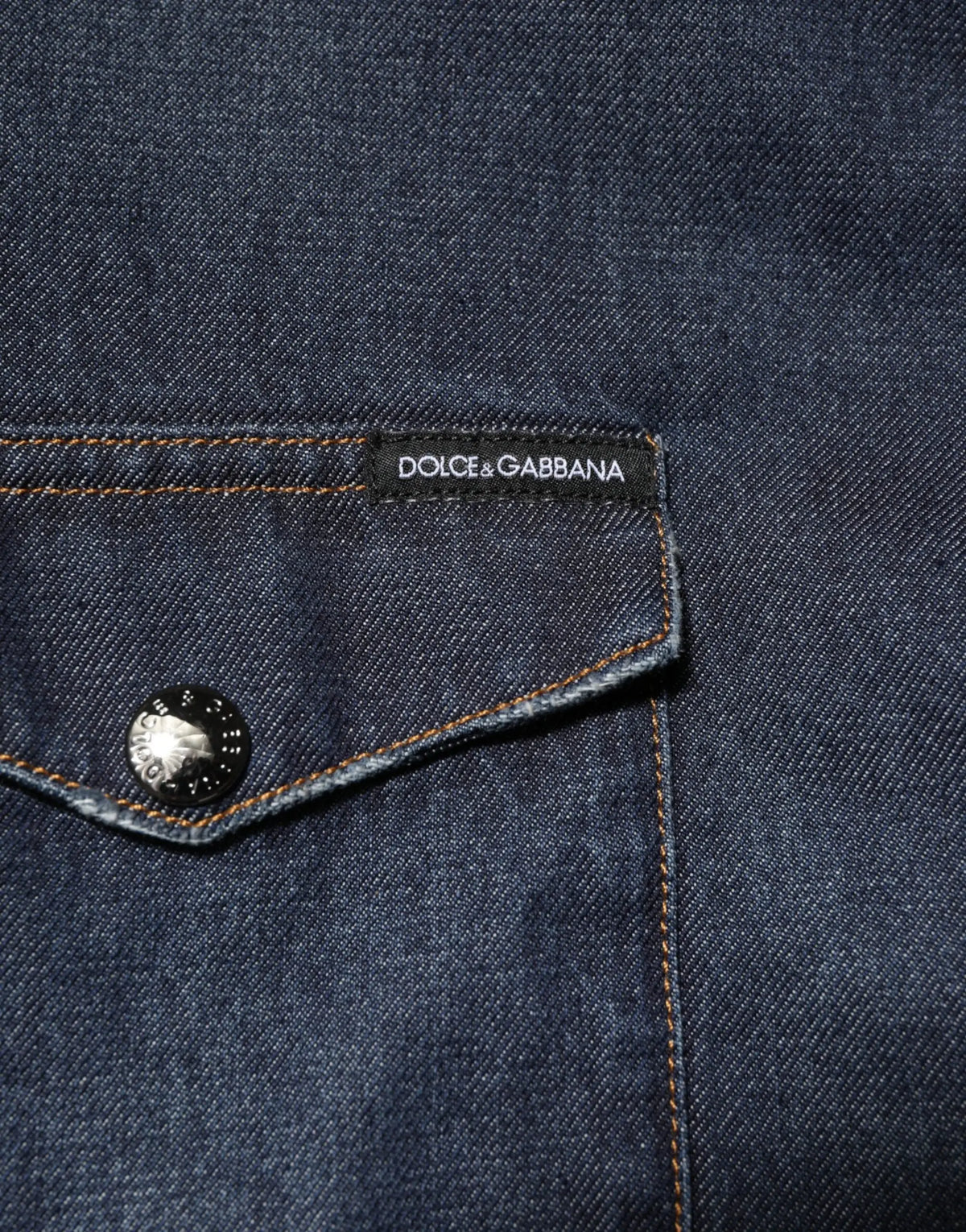 Poche de veste en jean bleu foncé avec étiquette noire dolce & gabbana et bouton argenté sur chemise homme casual