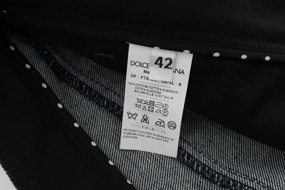Étiquette de soin blanche rectangulaire avec texte noir attachée à un jean torero capri en denim bleu coton dolce & gabbana