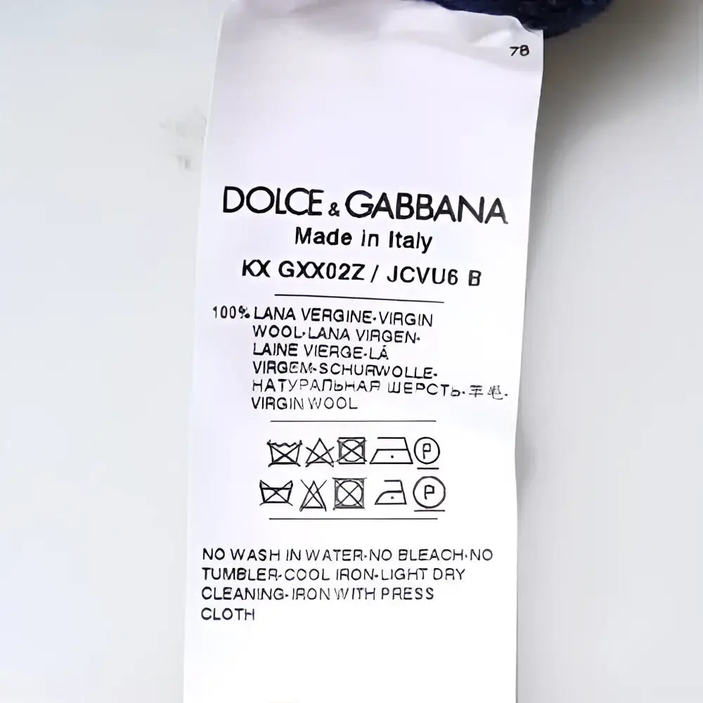 Étiquette blanche dolce & gabbana indiquant pull bleu en laine vierge 100% fabriqué en italie