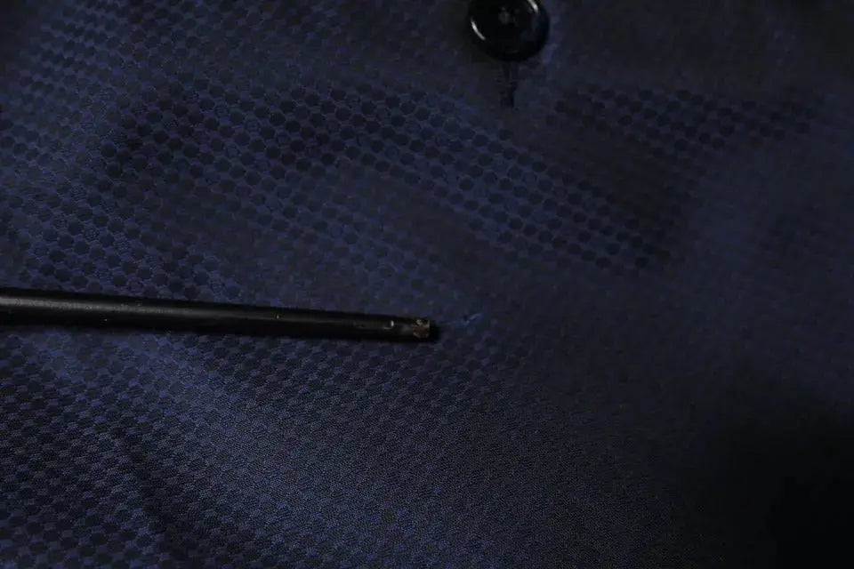 Un stylo noir élégant posé sur un tissu bleu foncé texturé à côté d un pantalon de smoking formel bleu en polyester dolce gabbana