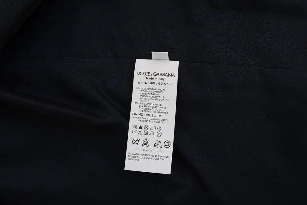 Étiquette de soin rectangulaire blanche avec texte noir attachée à un gilet dolce & gabbana bleu en laine stretch